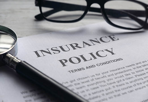 Insurance paperwork on a desk with glasses.
