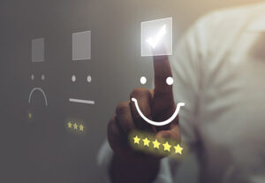 Three different faces symbolizing moods. A person pressing the happy face.