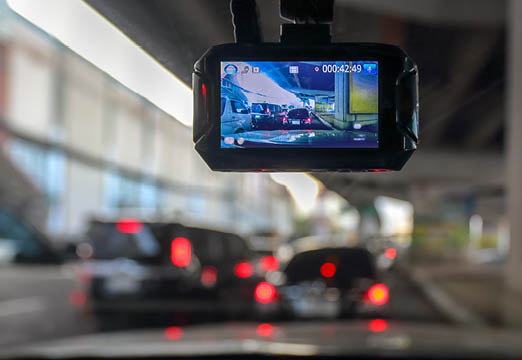 A small camera connected to a windshield recording the traffic.