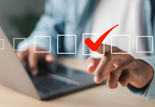 A man in professional dress touching on of many illustrated box to create a check mark.