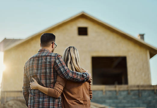 A couple looking at the outside of the home they are building