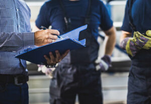 Three construction workers in a circle discussing something in a binder.