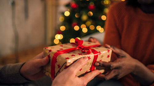 Two people passing a wrapped present during the holidays