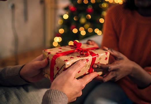 Two people passing a wrapped present during the holidays