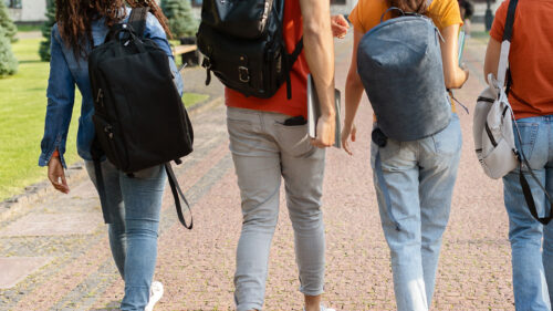 students wearing backpacks while walking away