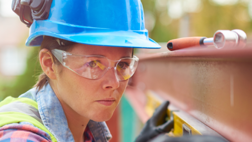 A female construction worker wearing a hardhat and protective eyewear