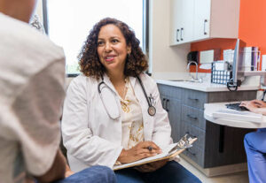 A female doctor talking to a patient in a welcoming exam room.