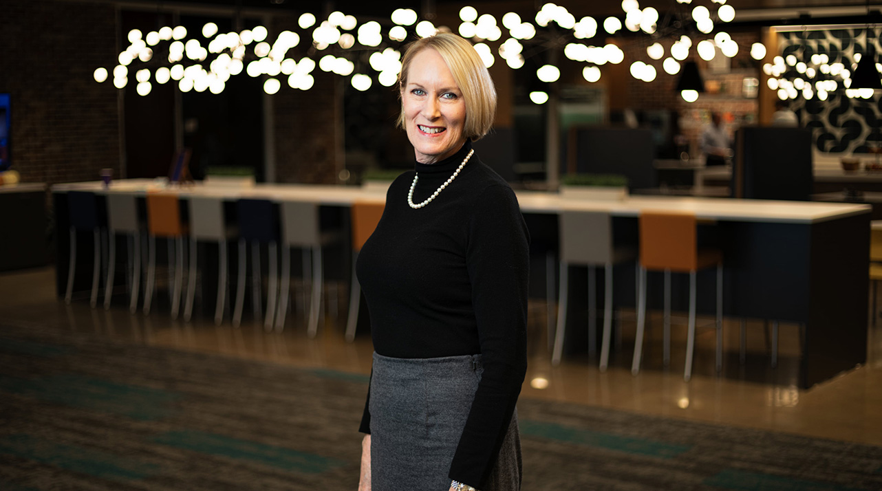 Paula Dixon in a black turtleneck and chunky necklace smiling.