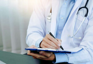 A doctor writes on a clipboard.