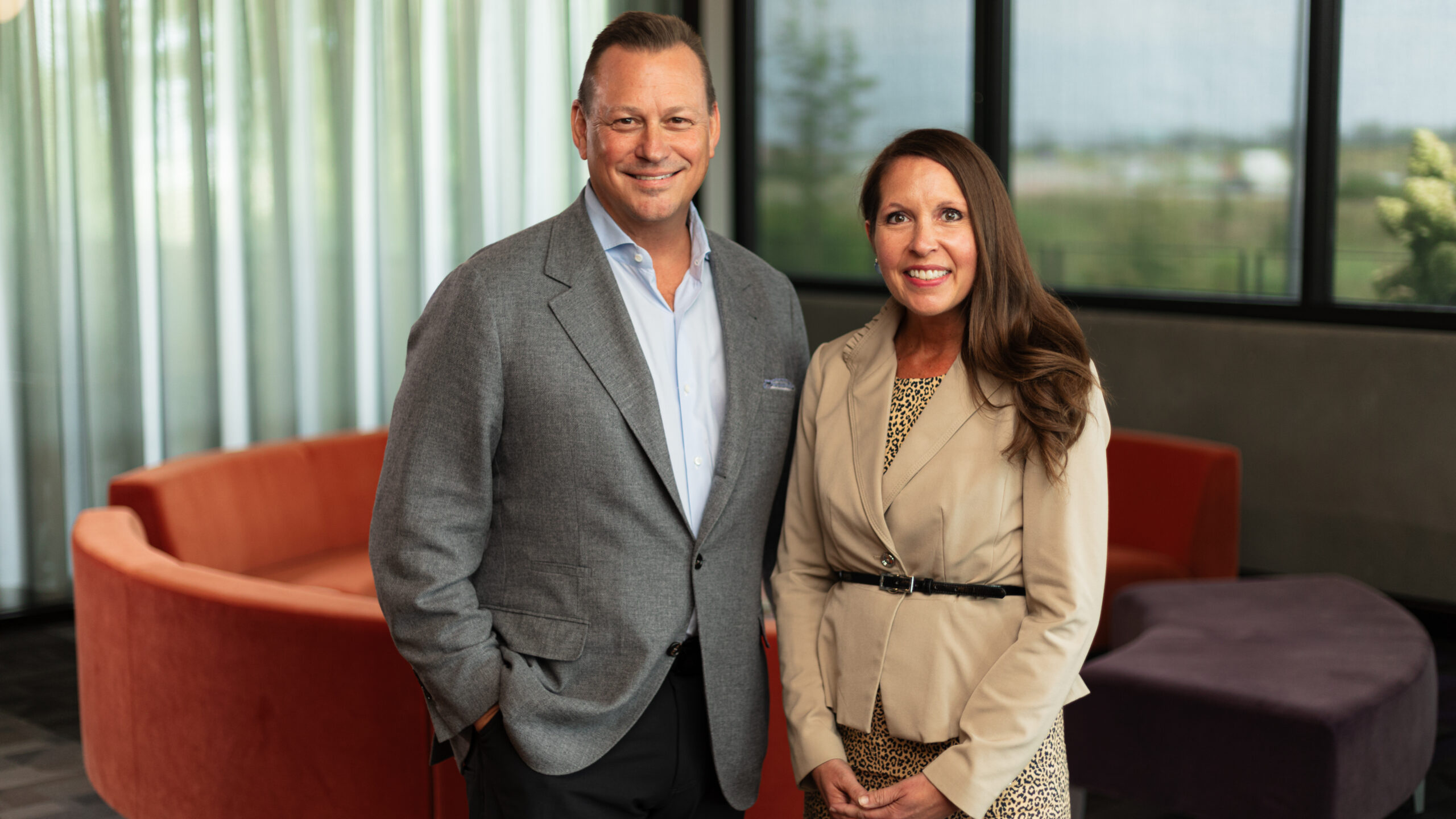 Susan Hatten and Tom Stewart smiling together in business professional clothes.