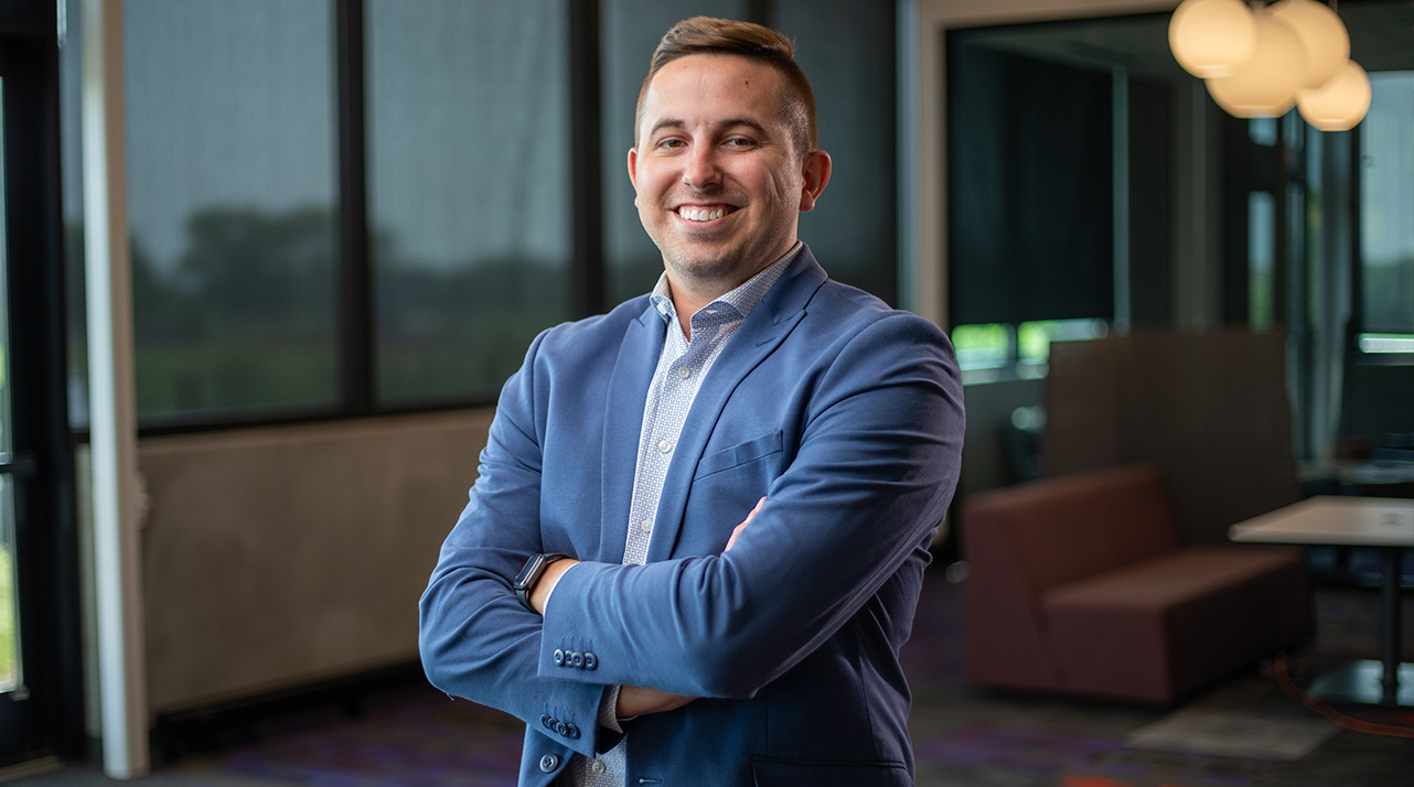 Ross Enderson in a blue blazer with his arms crossed smiling