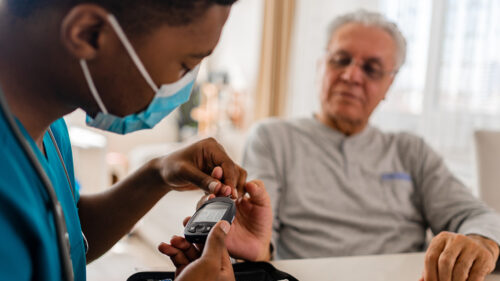An older man getting his blood sugar tested by a health professional.