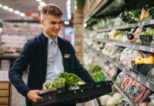 A grocery employee stocking vegetables