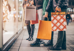 People looking at a shopping window carrying bags of previous purchases. It looks cold.