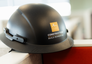A black hardhat with an orange Holmes Murphy Construction logo