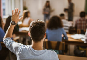 A young man raising his hand in class.