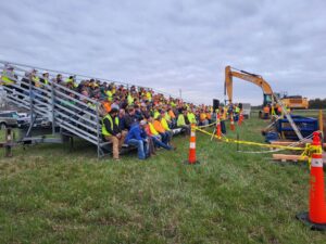A group of construction workers sitting on bleachers, listening to OSHA presentation.