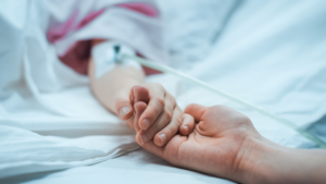 A young patient holds hands with their parents in the hospital