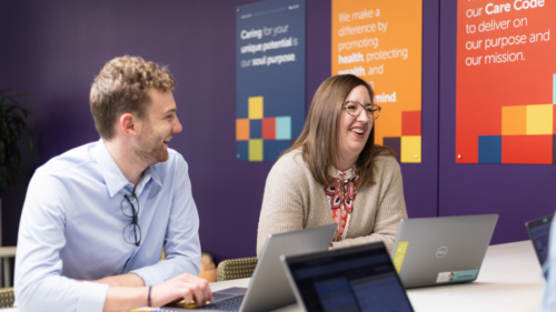 Two Holmes Murphy employees smile and chat in a colorful office space.