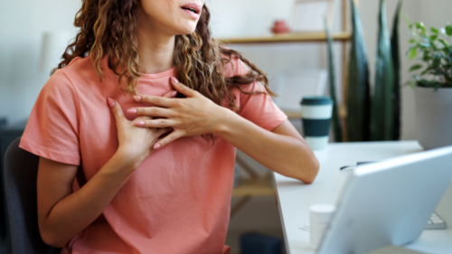 A person puts their hands on their chest while talking with a healthcare professional on a telehealth call.