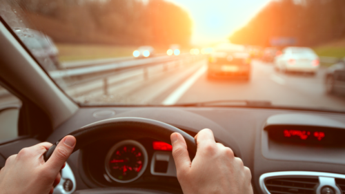 A driver holds the steering wheel in highway traffic.