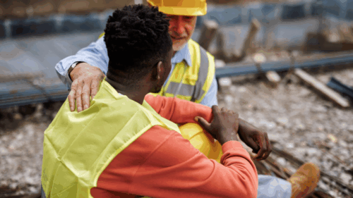 A construction worker comforts his colleague on a jobsite.