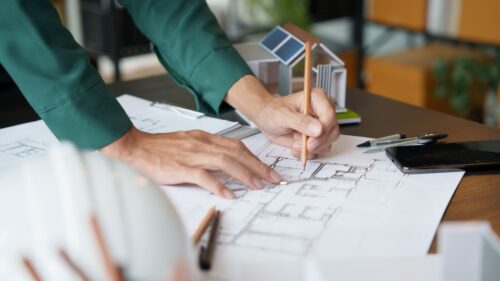 An architect makes a note on a blueprint with a pencil