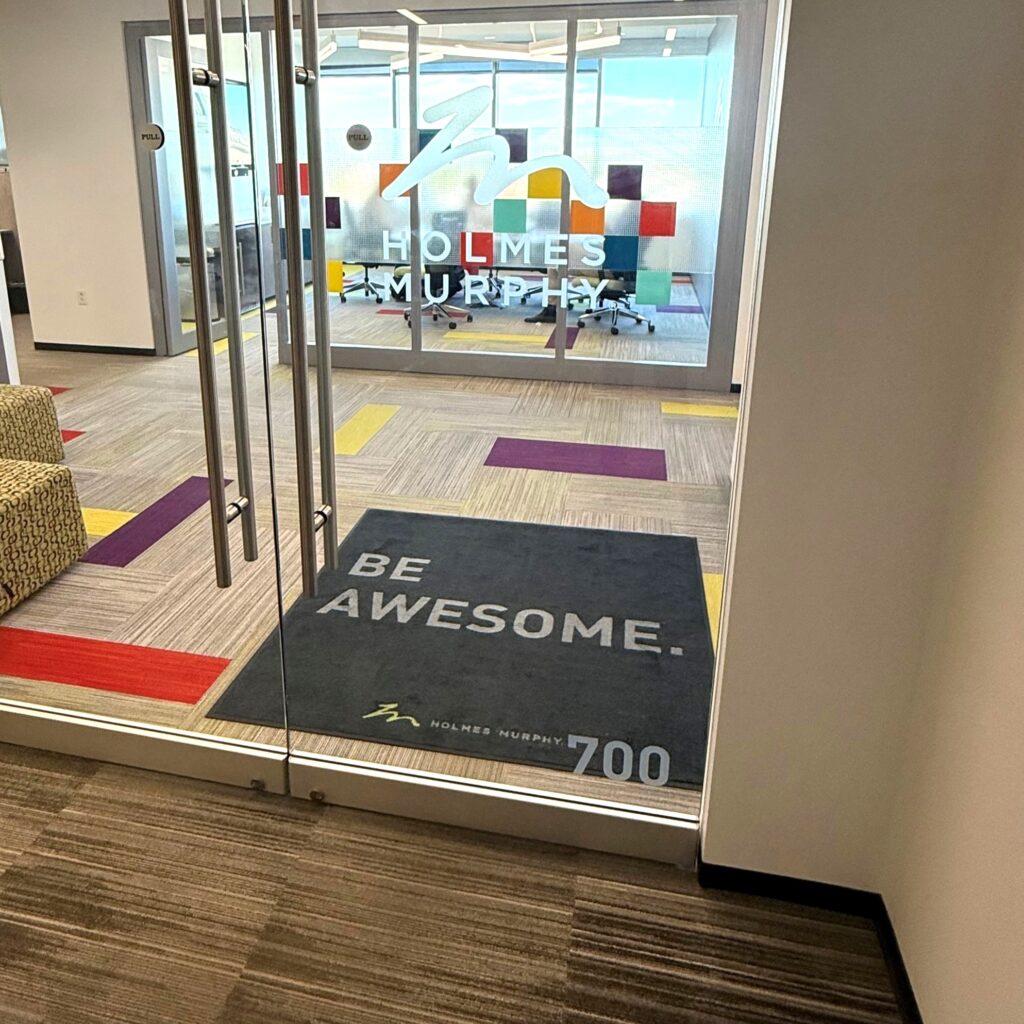 A black mat with BE AWESOME written in the center at the Holmes Murphy Cedar Rapids office