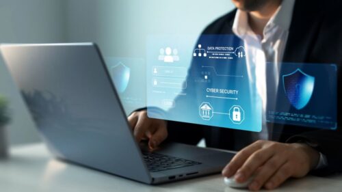 A person sits at their laptop with cyber security and data protection images