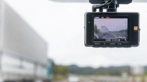 A forward-facing dashcam shows a semitruck driving on the left side of the road
