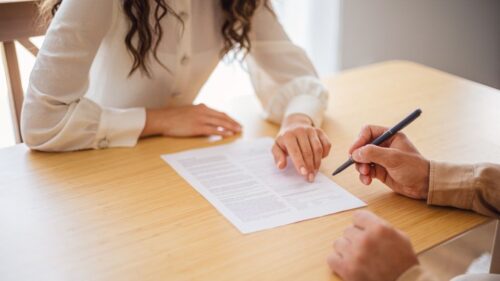 Two people sit at a table and review a contract