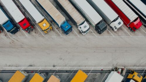 A row of semi-trucks parked diagonally in a parking lot