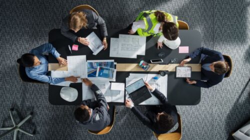 A team of architects and engineers look at project documents on a table