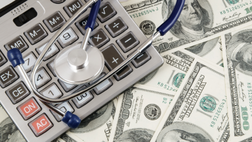 money laid out with a calculator and stethoscope on top