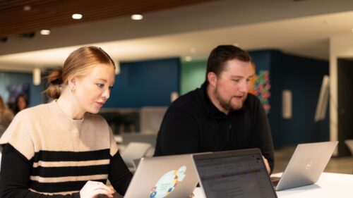 Two young professionals look at their laptops