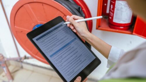 An inspector takes notes on a tablet during a loss control visit.
